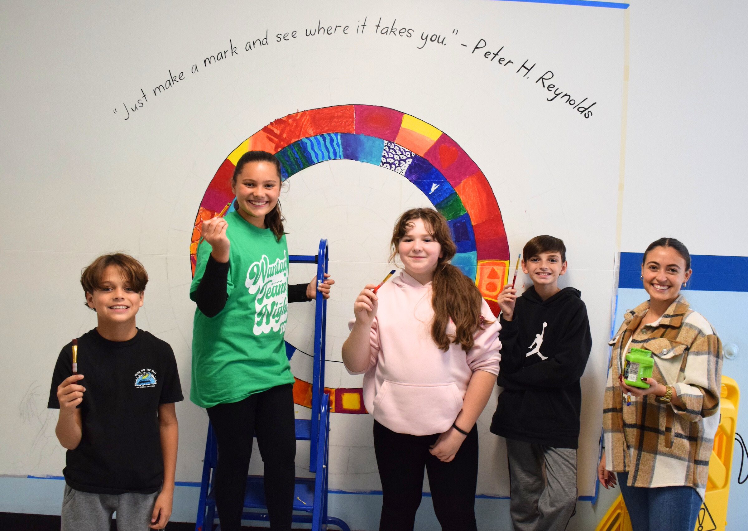 kids in front of painted wall holding paint brushes